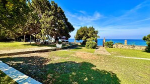 A coastal park with a paved walkway, seating areas, and a view of the sea.
