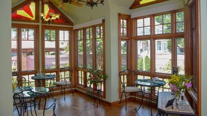 A sunroom with large windows, wooden beams, and a ceiling fan. - The Towers Bed & Breakfast (Milford)