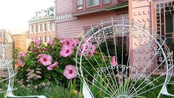 A pink house with a white fence and pink flowers in front.