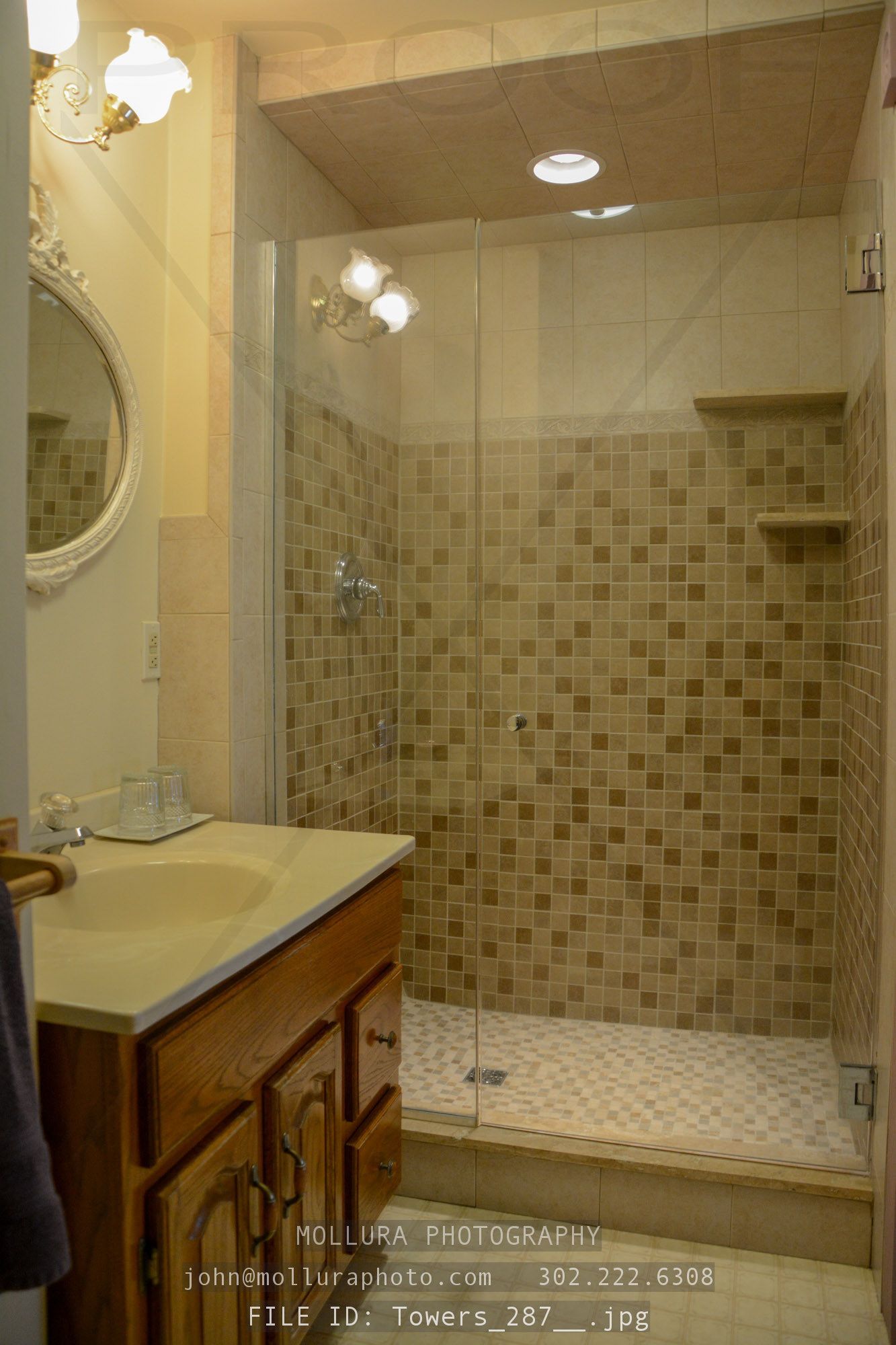A bathroom with a glass-enclosed shower, a vanity with a mirror, and a tiled floor.