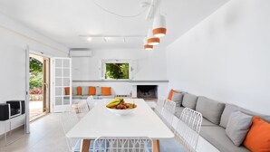 A modern kitchen with a dining area, white cabinetry, and a central island with fruit.