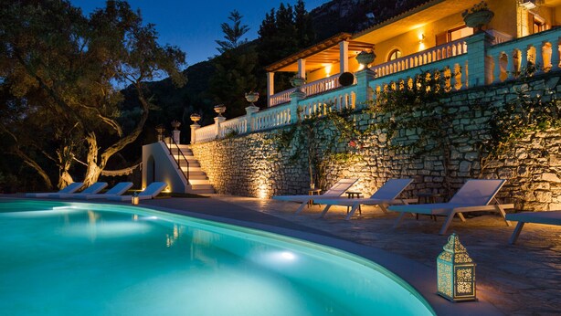 A pool area with lounge chairs and a stone wall.