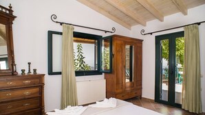 A bedroom with a large bed, wooden dresser, and a view of the outdoors through a sliding door. - Agrilos House - Amazing sea view - Sleeps 4 (Mirsini)