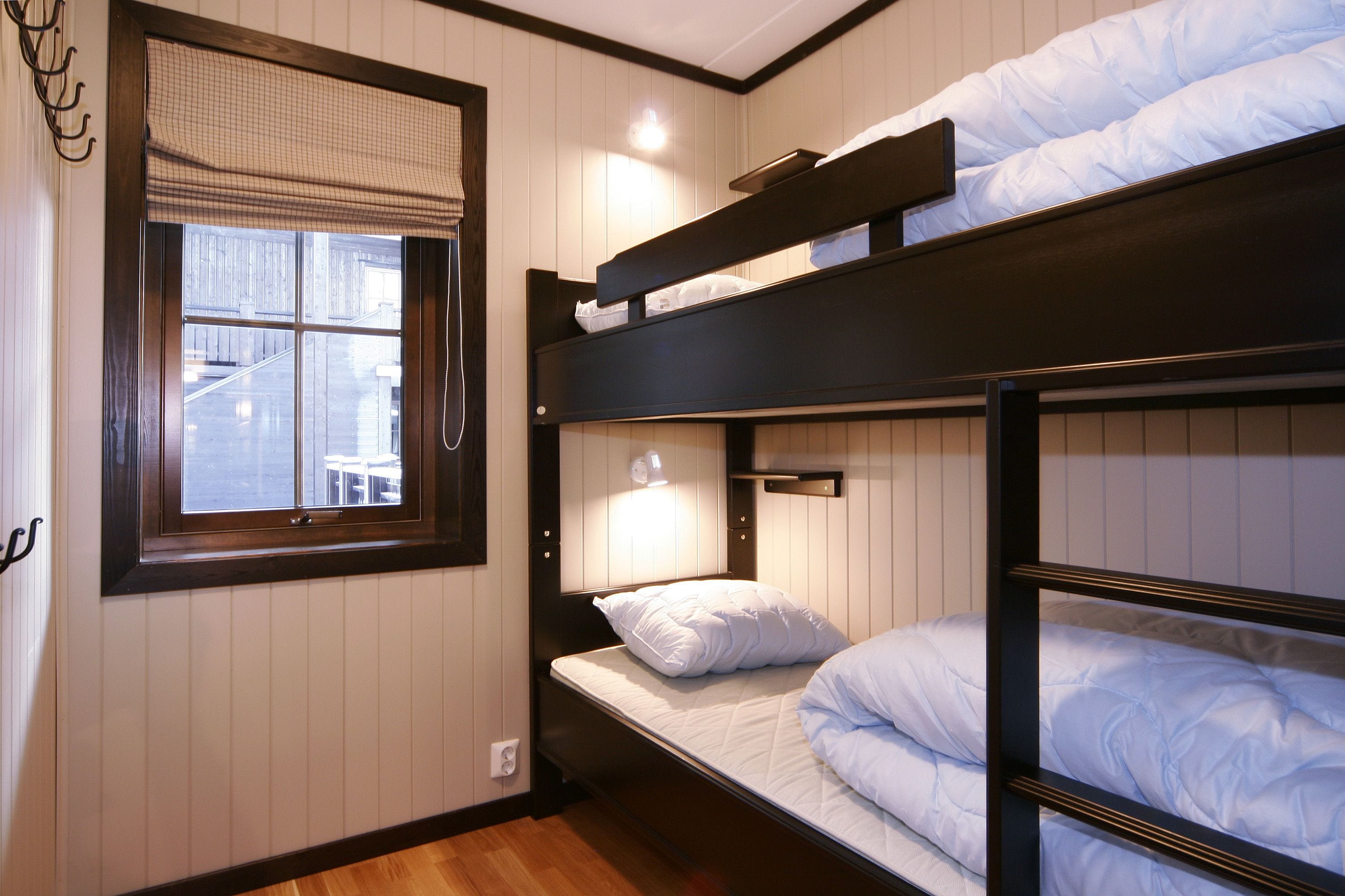 A bunk bed room with a window and a wall-mounted light.