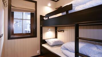 A bunk bed room with a window and a wall-mounted light.