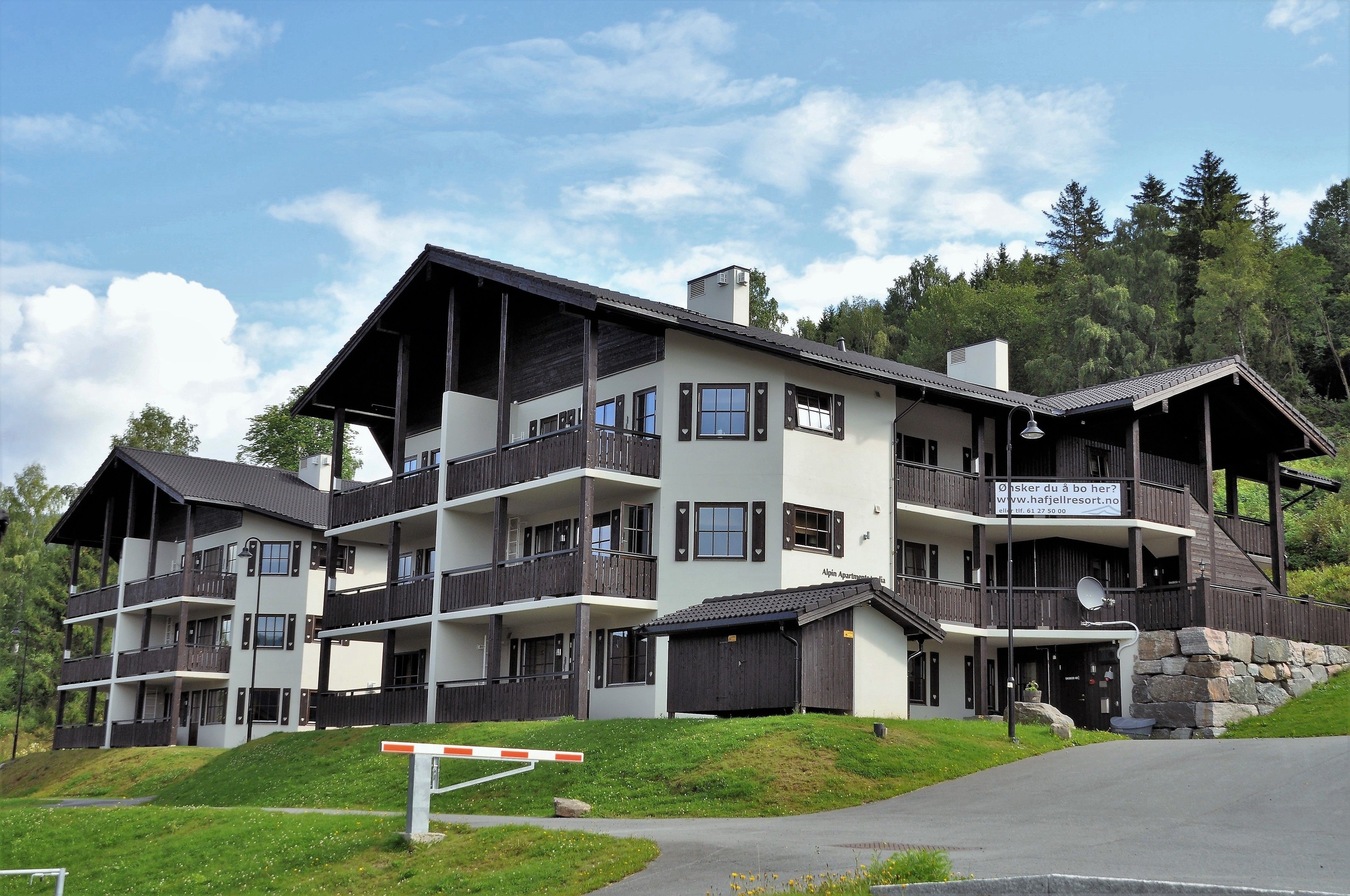 Un hotel de varios pisos con balcones, fachada de piedra y un cartel que anuncia una página web.