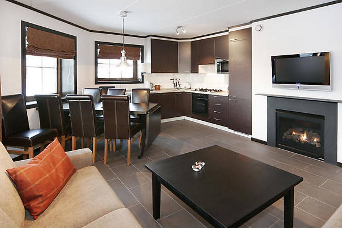 Una sala de estar moderna con sofá, una mesa de centro, chimenea y una zona de cocina con comedor.