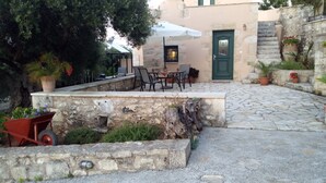 A stone patio with outdoor furniture, a green door, and potted plants. - TZITZIFES OLD STONE MANSION (Χανιά)