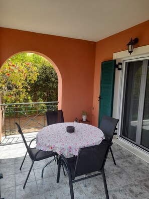 A round table with a floral tablecloth, four black chairs, a small potted plant, and a metal railing.