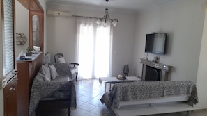 Un salon comprenant un canapé, une table à manger, un téléviseur fixé au mur et une cheminée.