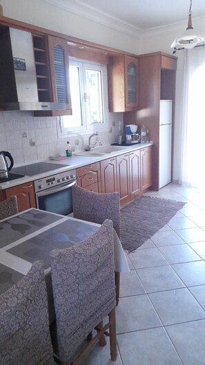A kitchen with wooden cabinets, a stove, a sink, and a dining table with chairs.
