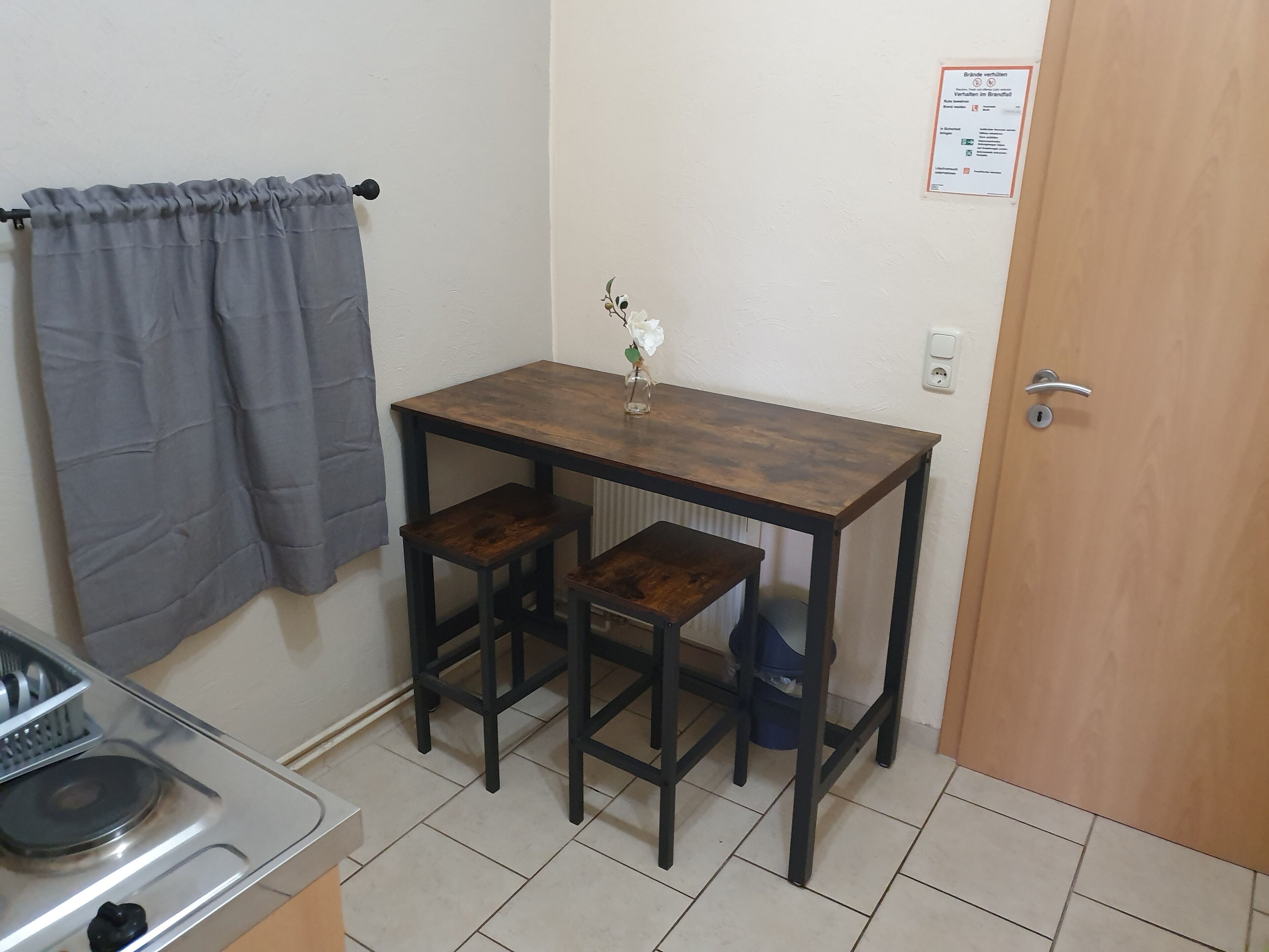 Une petite cuisine équipée d’une cuisinière à gaz, d’un évier et d’une table avec deux tabourets.