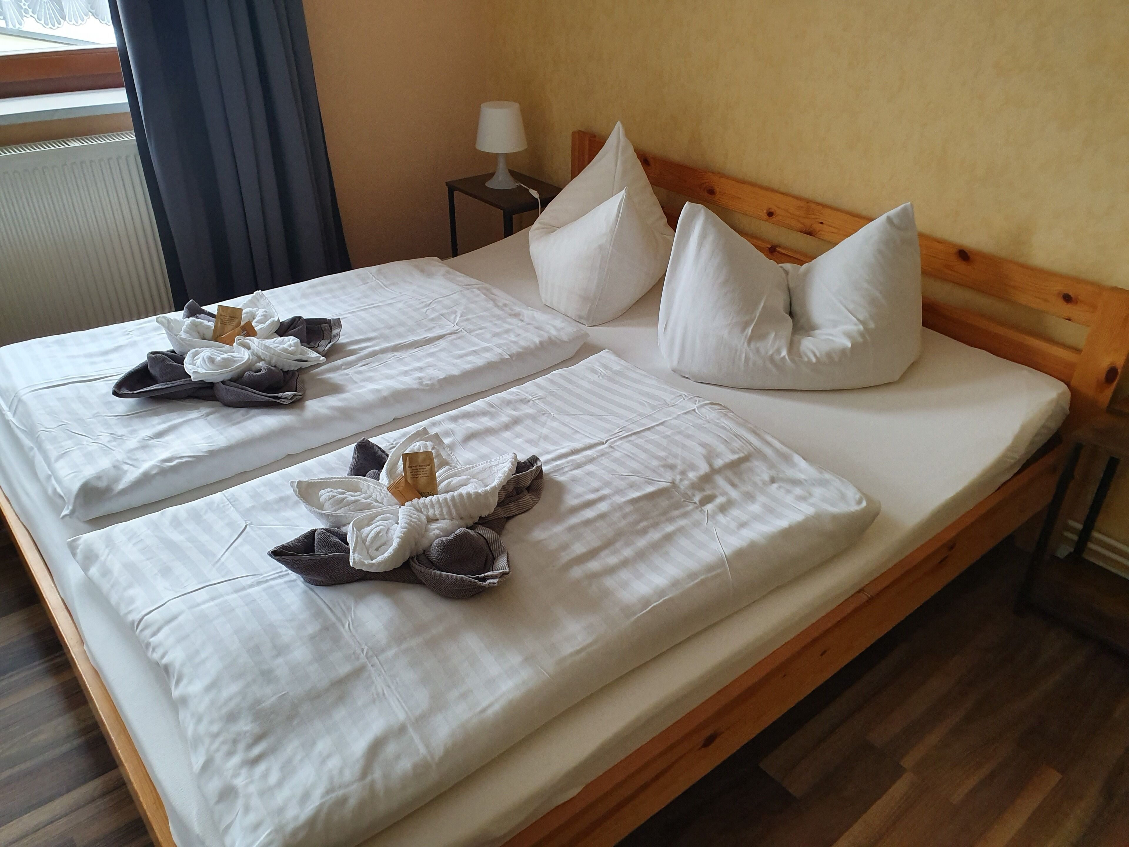 Ein Doppelbett mit weißer Bettwäsche, zwei Kissen und ein Nachttisch mit Lampe.