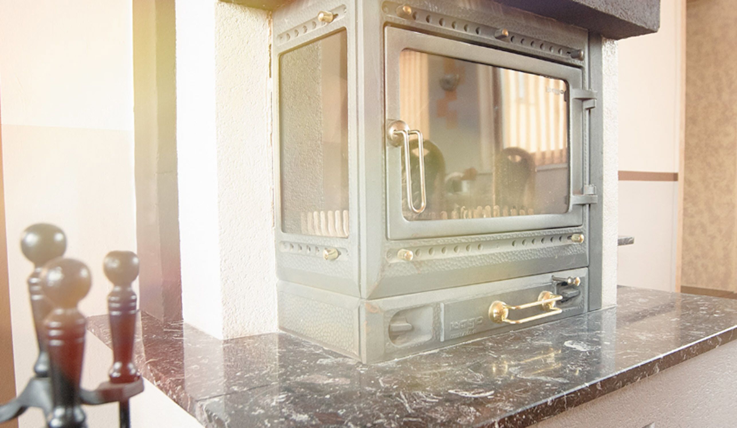 A vintage stove with a glass door and brass handles, placed on a marble countertop.