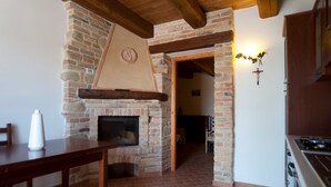 A kitchen with a brick fireplace, wooden beams, and a stove.