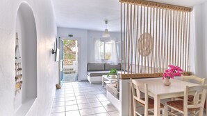 Een modern, minimalistisch interieur met een betegelde vloer, een houten eettafel met stoelen, een hangende touwdecoratie en uitzicht op het buitengebied door een raam.
