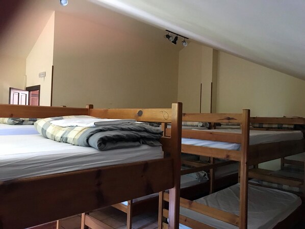 Un dormitorio con literas, una lámpara en el techo y una puerta al fondo.