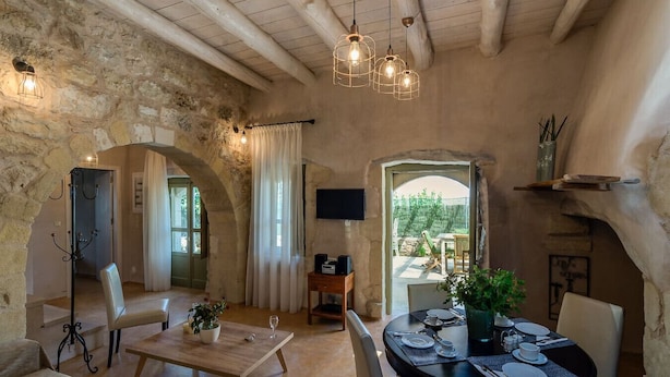 A rustic interior with stone walls, a dining area with a table set for two, and a television mounted on the wall. - Traditional Villa w/Heated Pool, 5km to the Beach (Καστελλος)
