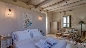 A bedroom with a bed, bedside tables, a wardrobe, a sofa, a chair, and a lamp. - Traditional Villa w/Heated Pool, 5km to the Beach (Καστελλος)