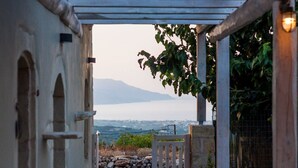 A stone gate leading to a covered outdoor area with a view of the sea and mountains. - Traditional Villa w/Heated Pool, 5km to the Beach (Καστελλος)