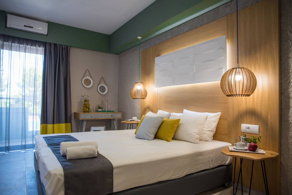 A modern hotel room with a large bed, bedside table, and a small desk.