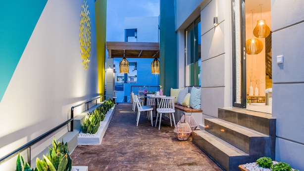 A modern outdoor seating area with a table and chairs, surrounded by plants and decorative lighting. - Sunshine Boutique Hotel (Hersonissos)