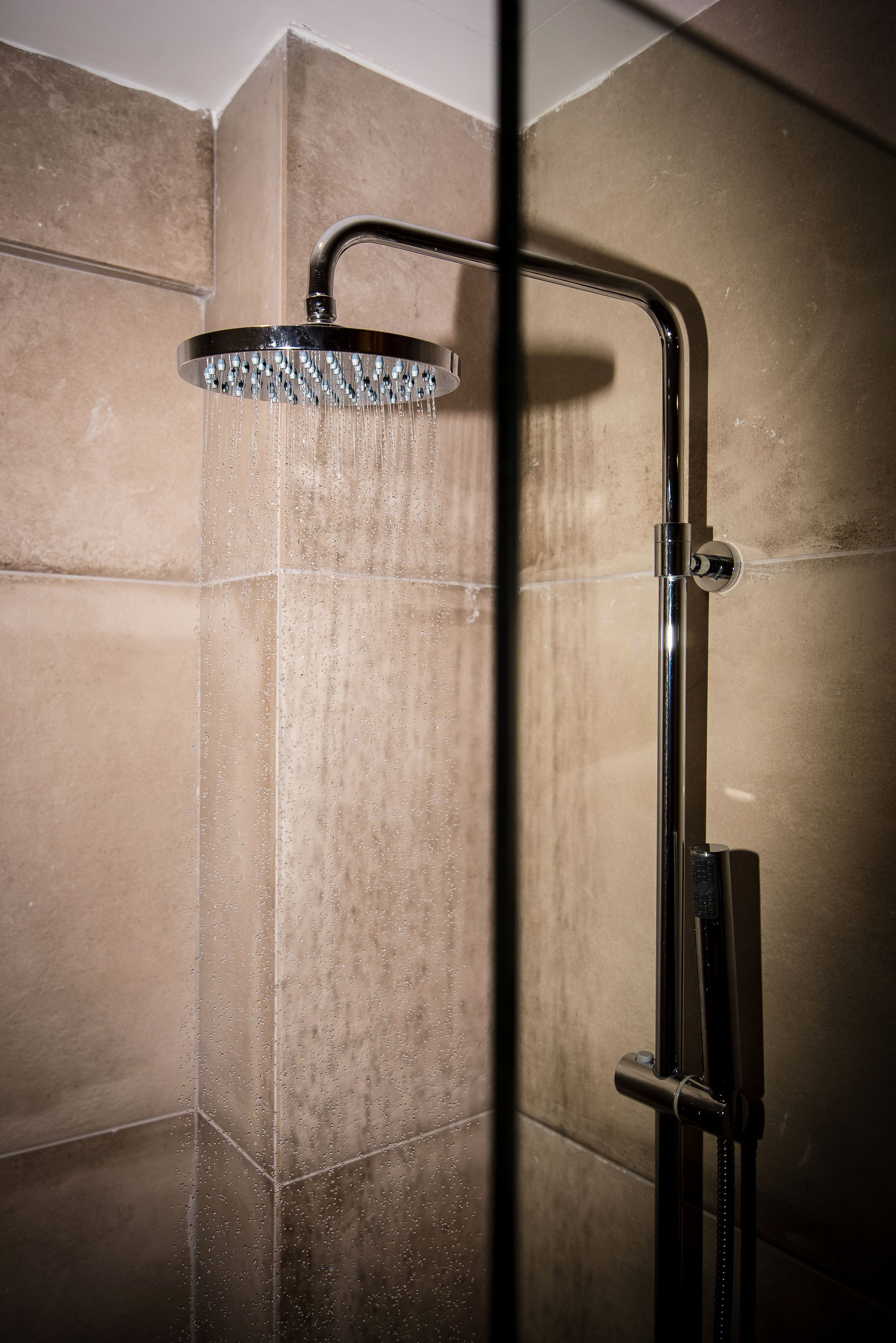 A shower with a curved head and a handheld showerhead.