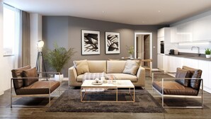 Ein modernes Wohnzimmer mit einer Couch, einem Couchtisch und Sesseln. Es gibt eine Küchenzeile mit Schränken und einer Spüle.