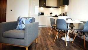 Ein modernes Wohnzimmer mit grauem Sofa und einem Essbereich mit weißem Tisch und grauen Stühlen.