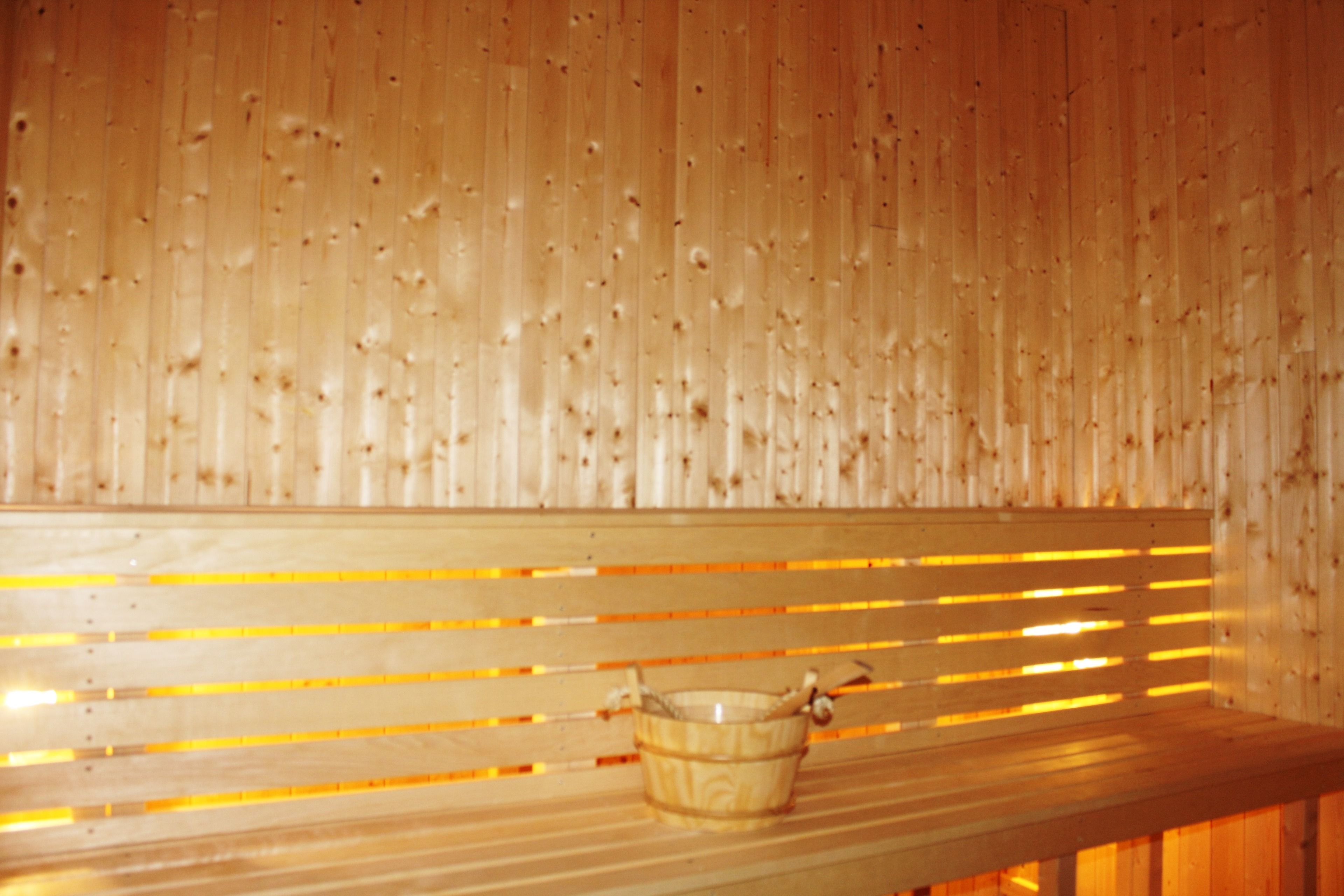 A wooden bench with a bucket in a sauna room.