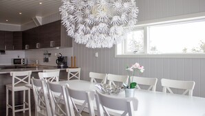 A modern kitchen with white cabinetry, a dining table with white chairs, and a unique white chandelier. - Hafjell Resort Hafjelltoppen Gaiastova (Øyer)