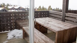 A wooden deck with benches and a glass door leading to a snowy landscape. - Hafjell Resort Hafjelltoppen Gaiastova (Øyer)