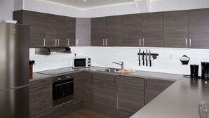 A modern kitchen with dark wood cabinets, stainless steel appliances, and a white tiled backsplash. - Hafjell Resort Hafjelltoppen Gaiastova (Øyer)
