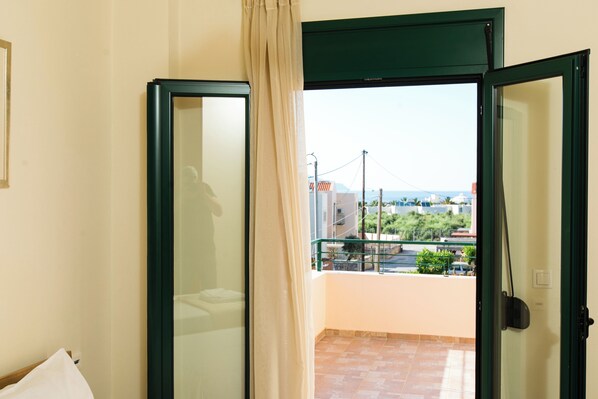 A room with a balcony, a bed, and a view of the cityscape.