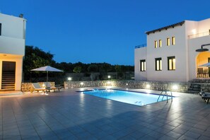 Una piscina con un muro de piedra y un edificio blanco con varias ventanas.