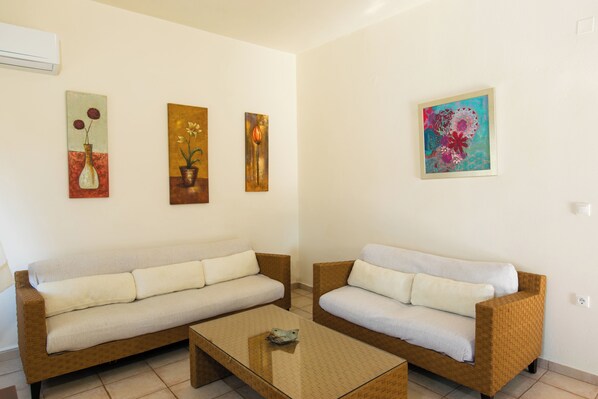 Una sala de estar con dos sofás, una mesa de centro y tres cuadros en la pared.