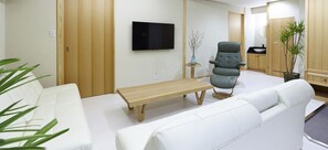 Ein modernes Wohnzimmer mit einer Couch, einer Bank, einem Fernseher und einer Holzkommode.