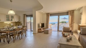 A modern living room with a dining area, a TV, and a balcony with a view of the sea. - New Villa Louisa by the sea, walking distance from sea and shops, no car needed! (Πάνορμος)