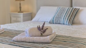 A neatly made bed with a striped pillow and a lamp on a bedside table. - New Villa Louisa by the sea, walking distance from sea and shops, no car needed! (Πάνορμος)