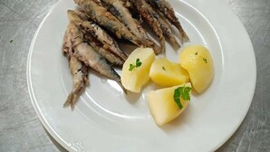 Ein Teller mit gegrilltem Fisch und gekochten Kartoffeln.