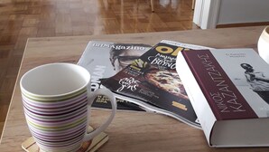 Une table en bois, sur laquelle se trouvent une tasse à rayures, un magazine et un livre.