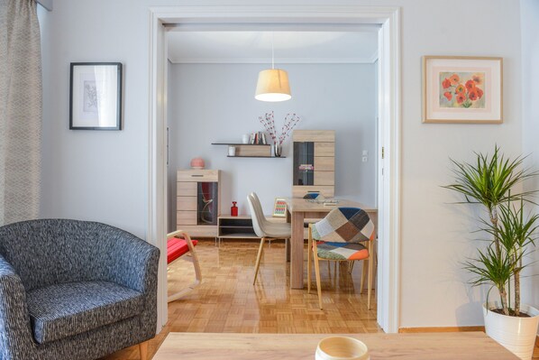 Un salon moderne avec un canapé, un coin repas comprenant une table et des chaises, et une plante en pot.