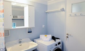 Une salle de bain équipée d’un lavabo, d’un miroir, d’un porte-serviettes et d’un lave-linge.
