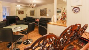 Ein modernes Wohnzimmer mit einem Glastisch, schwarzen Ledersofas und einer Chandelüster.