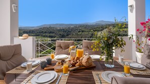 En frukost dukad upp på en terrass med en vacker utsikt över kullar och en klar himmel.