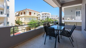 A balcony with a table and chairs, overlooking a residential area with multiple buildings. - City center apartment with ROOFTOP swimming pool (Χανιά)