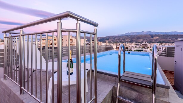 A rooftop pool area with a view of distant mountains and buildings. - City center apartment with ROOFTOP swimming pool (Χανιά)
