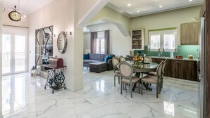 A spacious living area with a dining table, chairs, and a chandelier. - City center apartment with ROOFTOP swimming pool (Χανιά)