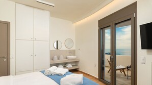 Een slaapkamer met een bed, een blauwe handdoek, een badkamer met een wastafel en spiegels, en een balkon met uitzicht.