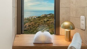 Een hoekzaal met een raam dat uitkijkt over een landschap, een houten bureau, een lamp en een stoel.